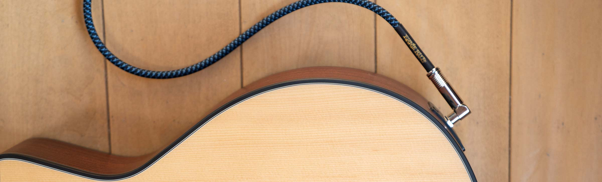 Close up of Ernia Ball braided cable hooked up to Ava Mahogany Live guitar.