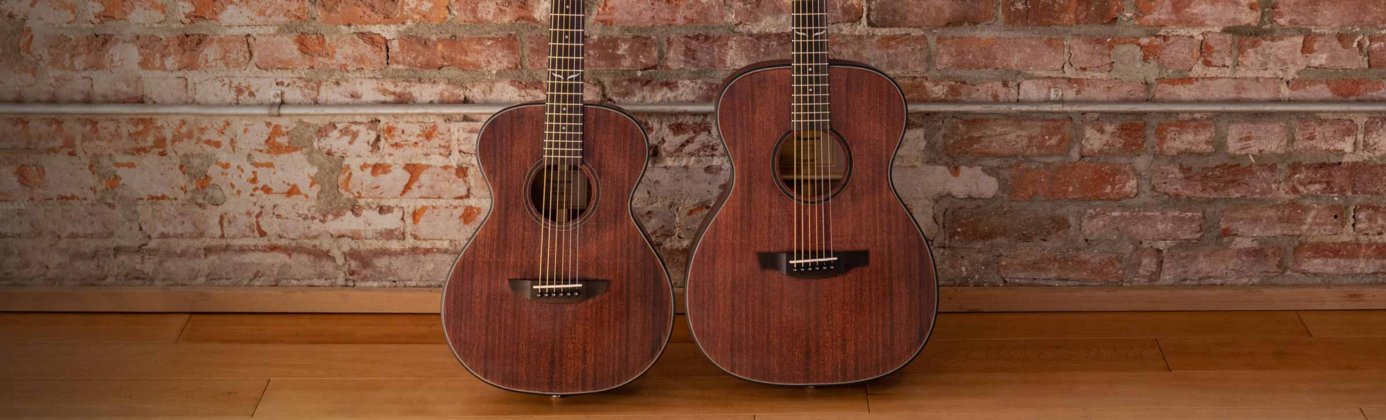 The Oliver Jr. Mahogany and Oliver Spruce guitars resting on a sofa.