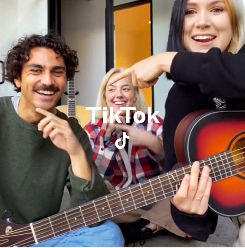 Photo of three people posing for a camera with TikTok text and logo overlaid
